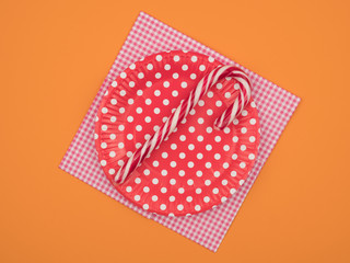 Christmas candy in a dish on a napkin. Orange background.
