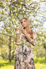 Fototapeta na wymiar Blond girl with long hair in spring blooming apple orchard