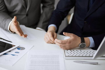 Business people using computer while working together in modern office. Unknown businessman or male entrepreneur with colleague at workplace. Teamwork and partnership concept