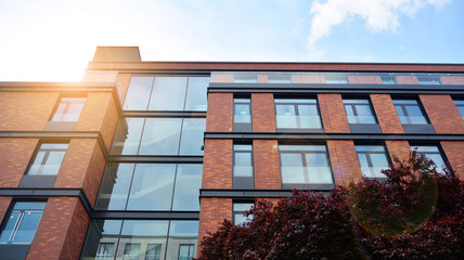 Modern apartment buildings on a sunny day with a blue sky. Facade of a modern apartment building. Glass surface with sunlight.