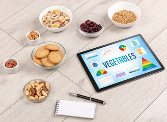 Organic food and tablet pc showing VEGETABLES inscription, healthy nutrition composition