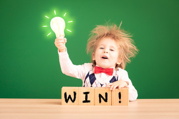 Bright idea! Happy child student against green chalkboard