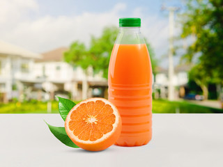 Bottle template with orange juice against the background of the nature. Near a bottle juicy orange with green leaves lies