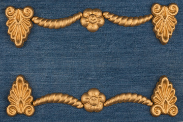 Frame made of gold-painted plaster molding lying on denim. Copy space. Top view.
