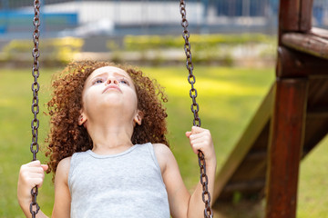 Caucasian girl playing on playground. Child playing alone in a park with social distance.