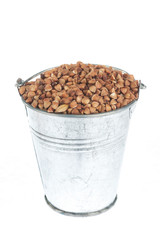 Fototapeta na wymiar Full bucket of buckwheat grains on a white background.