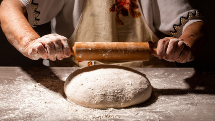 White flour flying into air as pastry chef in white suit slams ball dough on white powder covered...