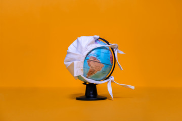 Weltkugel mit weißer Maske mit Blick auf Amerika auf orangenfarbenem Hintergrund