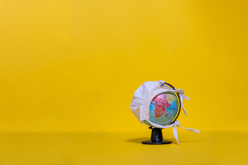 Weltkugel mit weißer Maske mit Blick auf Afrika auf gelbem Hintergrund