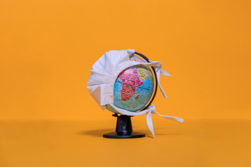 Weltkugel mit weißer Maske mit Blick auf Afrika auf orangenfarbenem Hintergrund