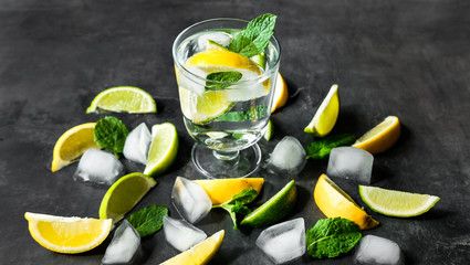 Refreshing iced infused water with lime, lemon and mint on dark background. Summer drink, cocktail concept.