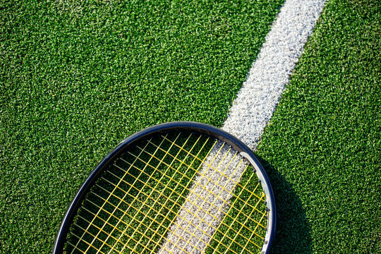Tennis racket on a green grass kort . summer sport concept. top view, free space for text .