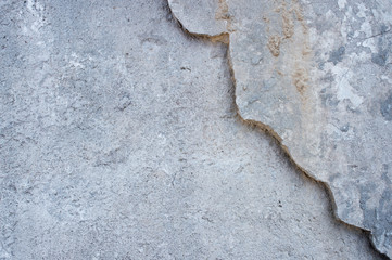 Grey concrete wall with a partially removed layer of surface with a beautiful curly border. Background.
