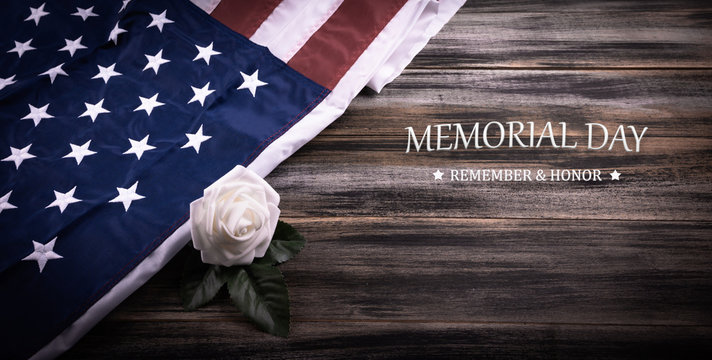 Vintage red, white, and blue American flag   with white rose and Text MEMORIAL DAY on a wood background.