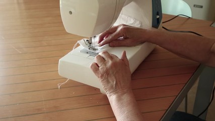 woman working at the sewing machine to make masks to protect from coronavirus