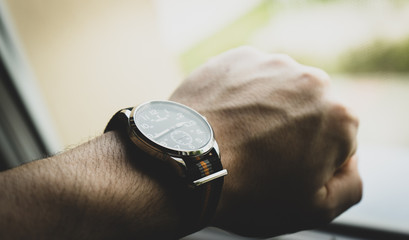 Men's watch on hand illuminated by the light from the window