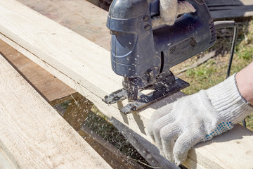 Carpenter at work, sawing wood with an electric saw.