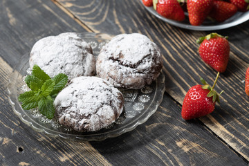 Homemade chocolate crinkles and strawberry in a glass saucer.