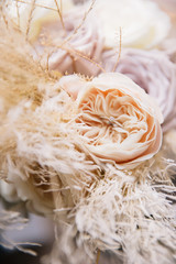 engagement ring inside a cream-colored peony rose in a composition with pampas grass
