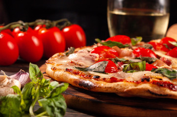 Homemade pizza with bacon and mushrooms on a wooden board. Tomatoes and basil.