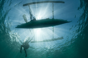 An outrigger canoe is silhouetted by bright sunlight in North Sulawesi, Indonesia. Millions of...