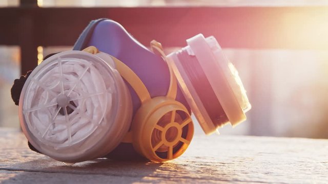 Personal protective half facepiece disposable industrial gas chemical respirator face mask on floor balcony with sunset background. Lens flare. Health care. Close-up.