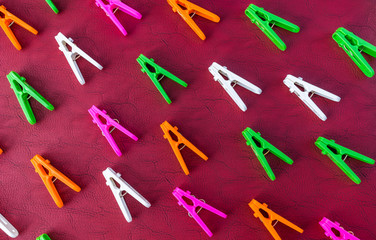 Colorful set of decorative plastic clothespins on a red background.