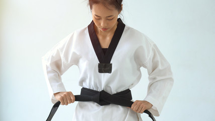 Young asian girl knots a black belt
