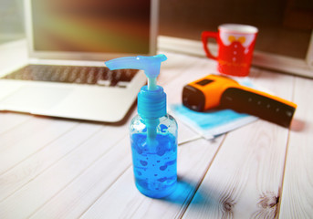 New normal with medical mask , hand sanitizer spray, Body thermometer, computer for work form home, and Covid-19 (Coronavirus) pandemic.