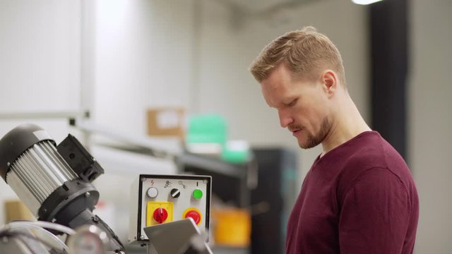 Tilt up side view shot of middle aged engineer working on laptop standing by cnc machine in laboratory