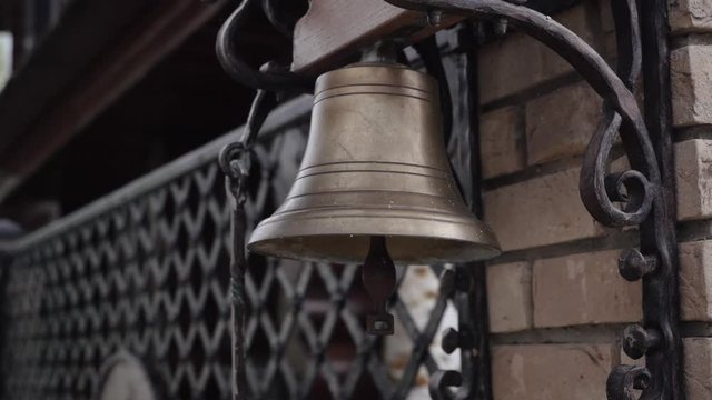A bronze bell hanging on the wall near the gate
