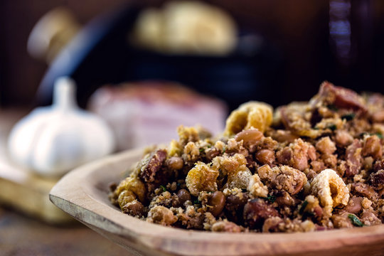 Beans with pork, called tropeiro beans in Brazil, typical Brazilian food, with ingredients, vegetables and vegetables in the background. Brazilian cuisine.