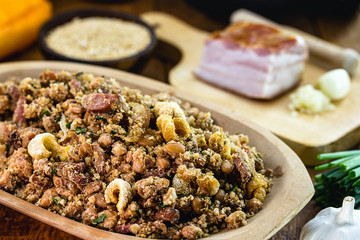 Beans with pork, called tropeiro beans in Brazil, typical Brazilian food, with ingredients, vegetables and vegetables in the background. Brazilian cuisine.