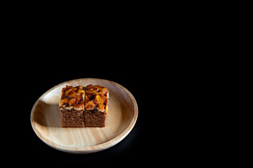 Toffee cake on wooden plate. black background.