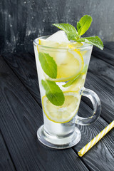 Infused or detox water with lemon and  mint  in the glass  on the dark  background. Closeup. Location vertical.