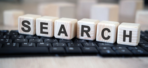 Search - text cubes stand on a black keyboard on a wooden table