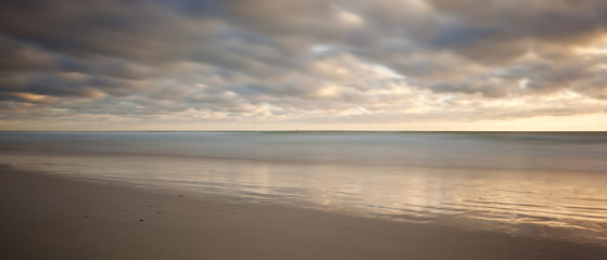 Naklejka na ściany i meble long exposure image of sandy beach and clouds