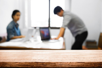 Empty wooden desk space over blurred office or meeting room background. Product display montage.