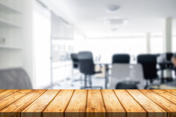 Empty wooden desk space over blurred office or meeting room background. Product display.