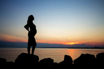 Silhouette of a  beautiful young pregnant woman on a background of the sea.