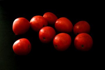 Red ripe tomatoes on black background. Top view with copy space