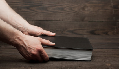 Old book bible in hand. On wooden background