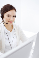 Call center. Casual dressed woman sitting and working in headset at customer service office. Business concept