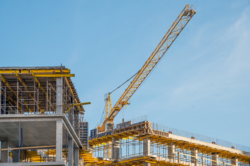 Fototapeta na wymiar Construction crane near new built house. Construction and developing horizontal photo