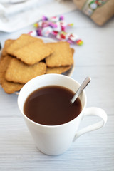White cocoa mug, in the background in a blur of cookies and candy