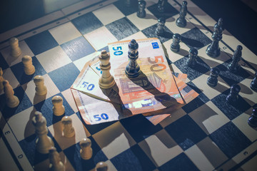 Top view of chessboard with arranged pieces, money with queens on top, agreement concept