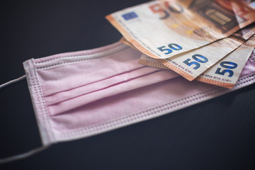 Medical face masks and money. Surgical face mask. COVID-19 Has Caused A Shortage Of Face Masks. Euro banknotes and Medical face masks