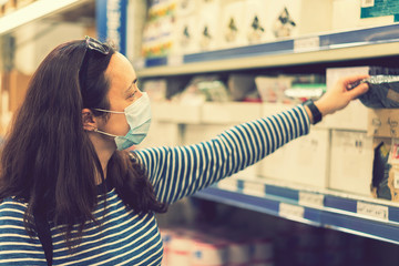 Woman in medical mask choosing goods in a store. Concept of shopping during quarantine at covid-19...