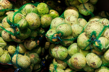 old white cabbage in bags. cabbage in bags at the market. The vendors use the bamboo strips to make a loop for carrying. forks of cabbage in nets harvesting for the winter, farming. toned