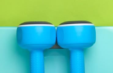 The concept of losing weight. Dumbbells on the floor scales. Studio shot on a green background.
